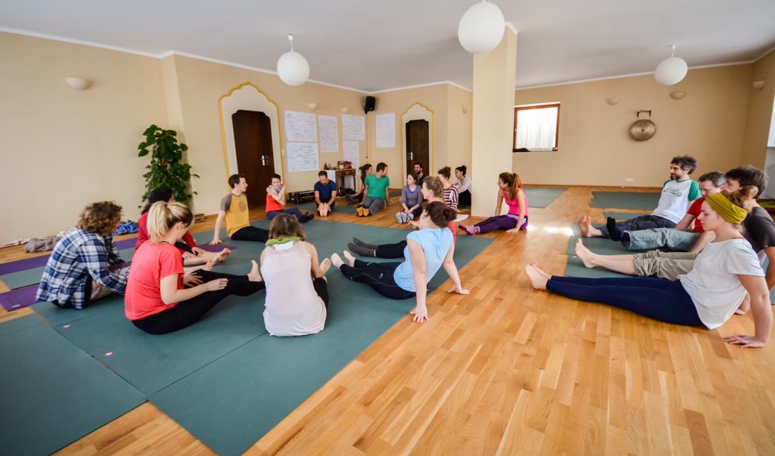 A full yoga room, the participants sitting in a circle on mats